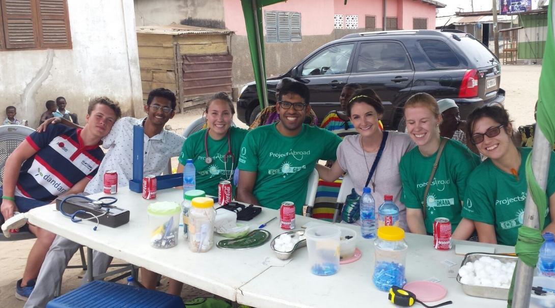 Tijdens de groepsreis Public Health, ontspannen de stagiaires tijdens een outreach. Als deel van hun groepsreis Public Health in Ghana, poseren de stagiaires voor een groepsfoto tijdens een pauze